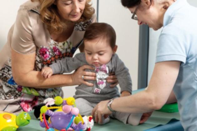 Un bambino è assistito da due adulti durante una sessione di gioco.